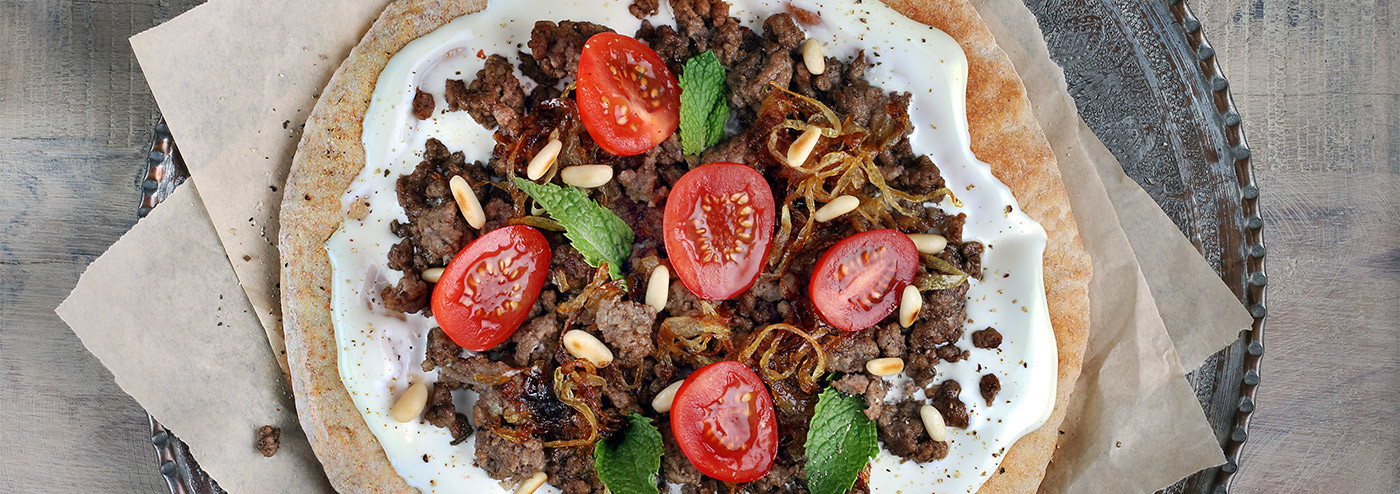 Arabic bread with cream cheese, minced meat, caramelized onions, tomatoes and mint